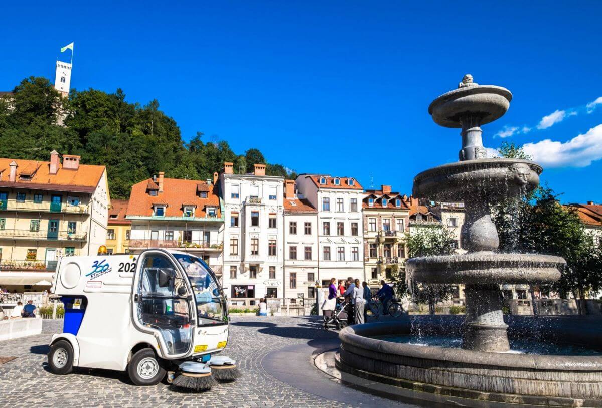 Road street sweeper standing near water fountain in Novi trg in Ljubljana.